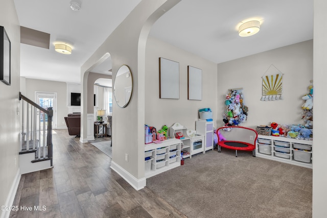 playroom featuring baseboards, arched walkways, and wood finished floors