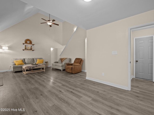 living area featuring high vaulted ceiling, wood finished floors, and baseboards