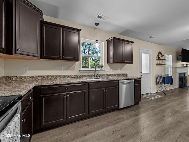 kitchen with light wood finished floors, visible vents, stainless steel dishwasher, a sink, and dark brown cabinets