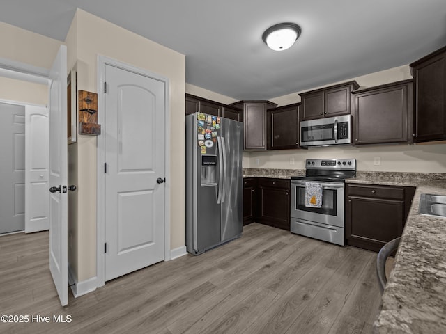 kitchen with light wood-type flooring, a sink, stainless steel appliances, and dark brown cabinets