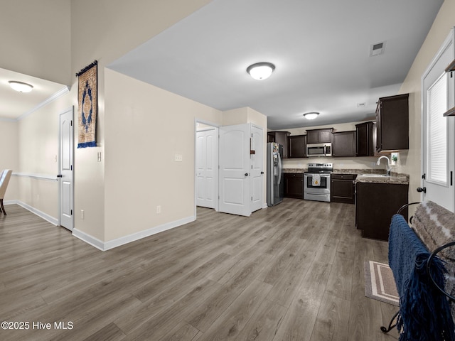 kitchen with baseboards, visible vents, light wood-style flooring, appliances with stainless steel finishes, and a sink