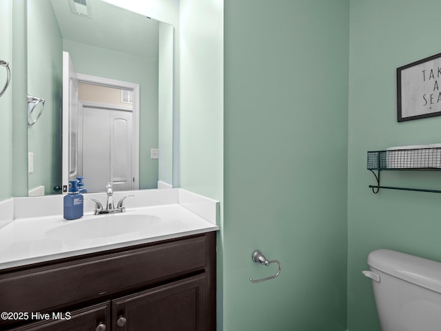 half bath featuring visible vents, vanity, and toilet