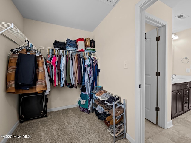 walk in closet featuring visible vents, a sink, and light carpet