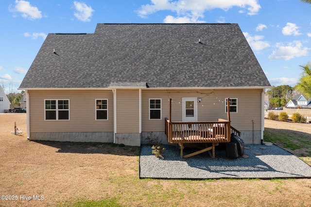 rear view of house with a shingled roof, a lawn, and a wooden deck