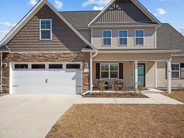 craftsman inspired home with a porch, a garage, stone siding, driveway, and board and batten siding