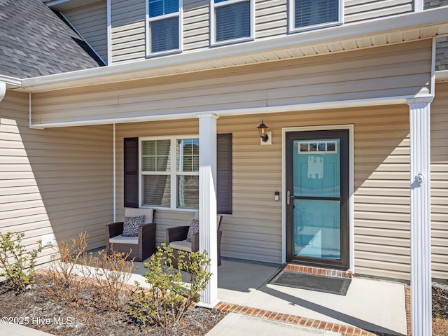 property entrance with covered porch and roof with shingles