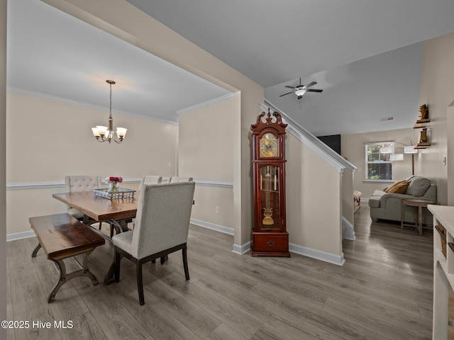 dining space featuring ceiling fan with notable chandelier, crown molding, wood finished floors, and baseboards