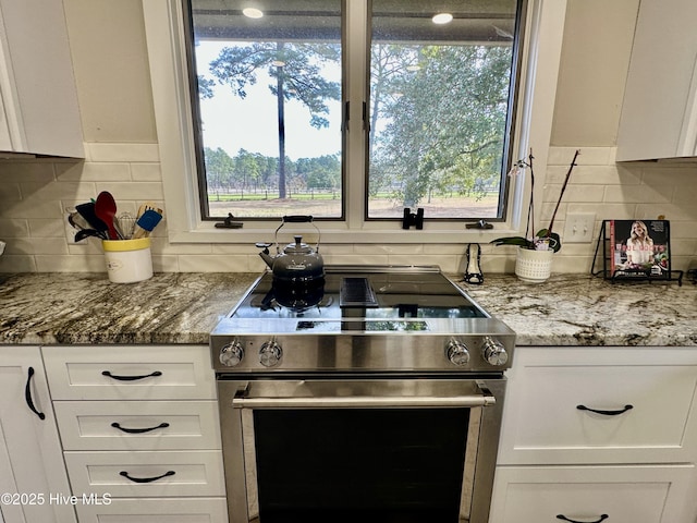 kitchen featuring stainless steel range with electric stovetop, stone counters, and white cabinets