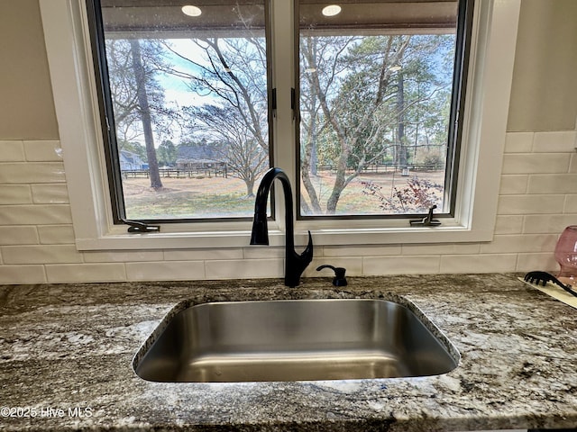 interior details featuring dark stone countertops, decorative backsplash, and a sink