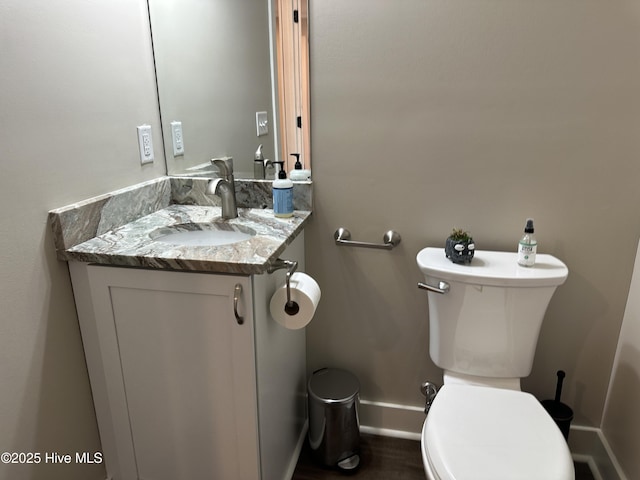 bathroom featuring toilet, baseboards, and vanity