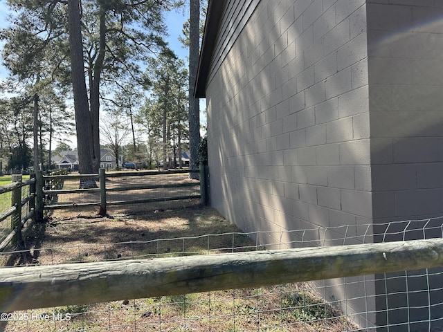 view of home's exterior with fence and concrete block siding