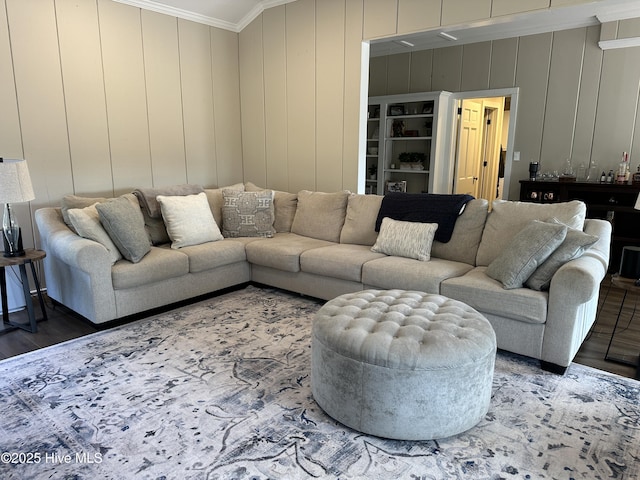 living room featuring ornamental molding, a decorative wall, and wood finished floors