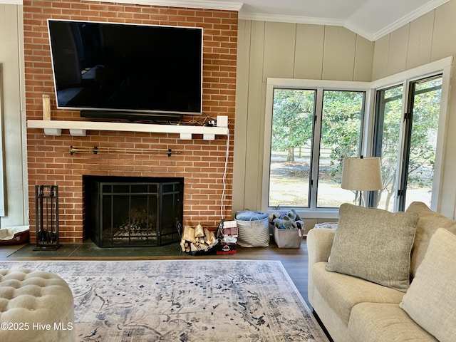 living room featuring ornamental molding, lofted ceiling, a fireplace, and wood finished floors