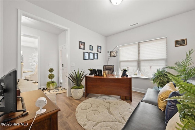 office area with wood finished floors, visible vents, and baseboards