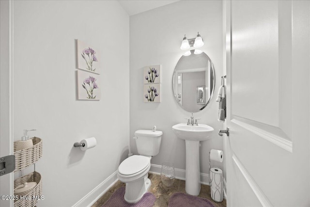 half bath with a sink, toilet, and baseboards