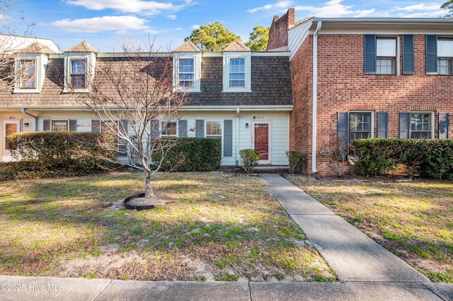 multi unit property featuring a shingled roof, brick siding, a chimney, and a front lawn