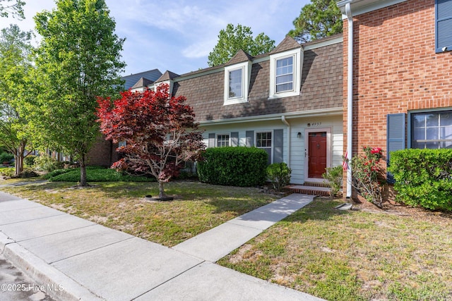 townhome / multi-family property with a front lawn, mansard roof, and a shingled roof