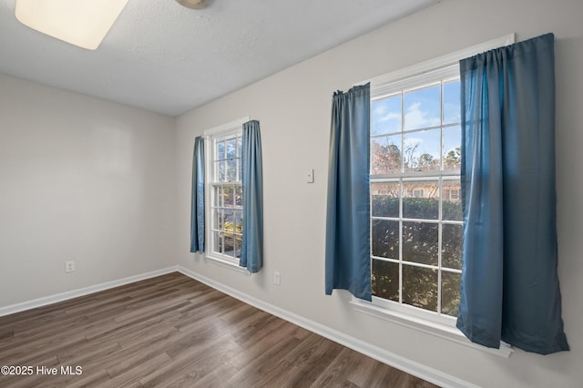 spare room featuring wood finished floors, a textured ceiling, and baseboards