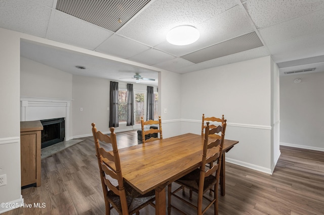 dining area with baseboards, a fireplace with flush hearth, visible vents, and wood finished floors