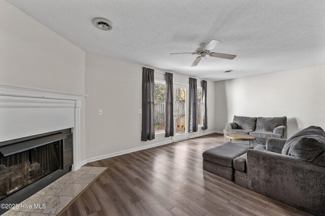 4937 Marlin Ct, Wilmington, NC 28403 - living room featuring a textured ceiling, wood finished floors, a ceiling fan, a fireplace, and baseboards