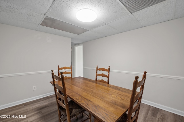 dining room featuring visible vents, baseboards, a paneled ceiling, and wood finished floors