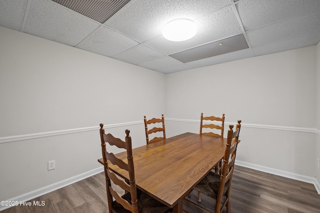 dining room with a drop ceiling, wood finished floors, and baseboards