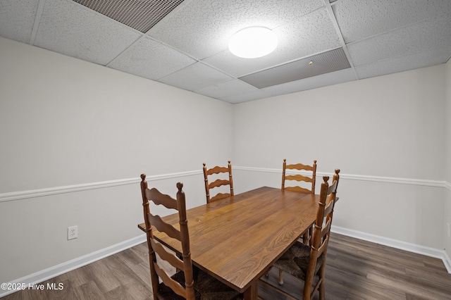 dining room featuring baseboards, visible vents, wood finished floors, and a drop ceiling