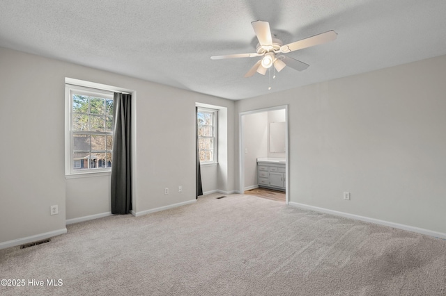 unfurnished bedroom featuring a textured ceiling, baseboards, visible vents, and light colored carpet