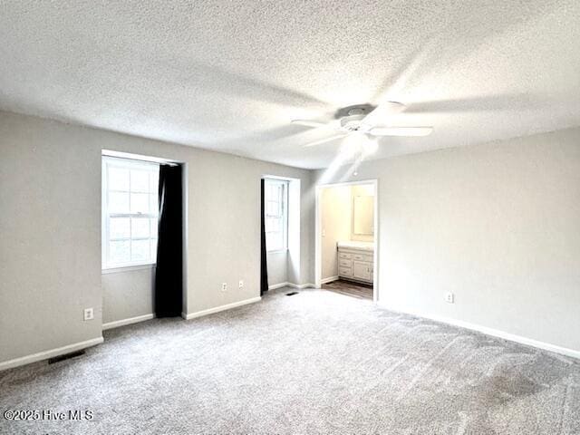 unfurnished bedroom with a textured ceiling, carpet flooring, and baseboards