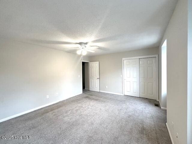 unfurnished bedroom with ceiling fan, carpet floors, a textured ceiling, and baseboards