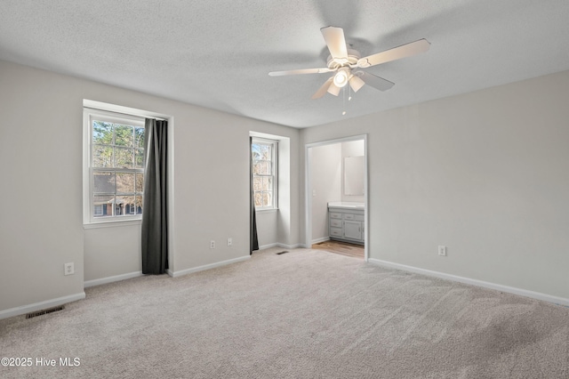 unfurnished bedroom featuring visible vents, baseboards, a textured ceiling, and light colored carpet