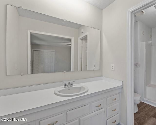 full bath with wood finished floors, vanity, a shower stall, and toilet