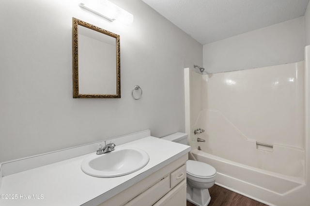 full bath with toilet, washtub / shower combination, vanity, and wood finished floors