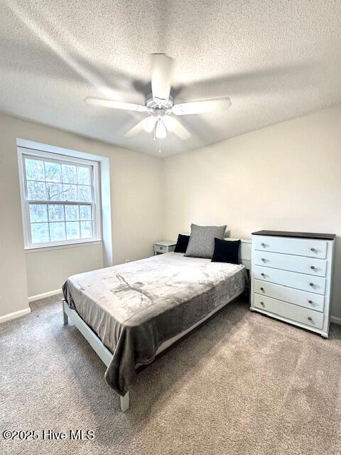 carpeted bedroom featuring a ceiling fan, baseboards, and a textured ceiling