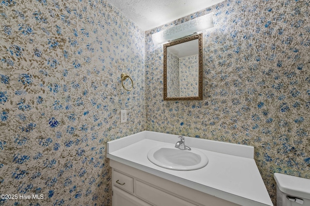 bathroom with wallpapered walls, vanity, and toilet