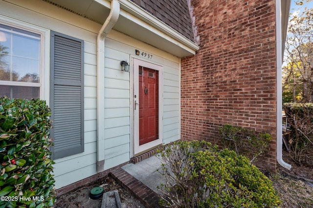 doorway to property with roof with shingles