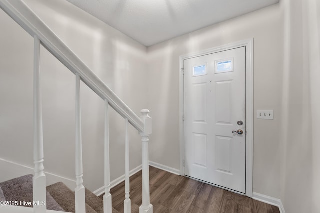 foyer entrance with baseboards, stairs, and dark wood-style flooring
