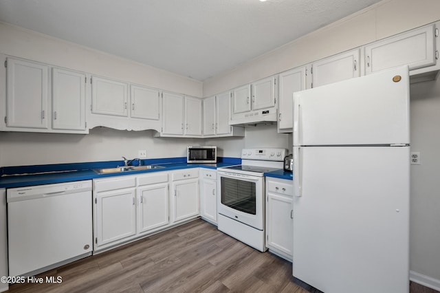 kitchen featuring white cabinets, a sink, wood finished floors, white appliances, and under cabinet range hood