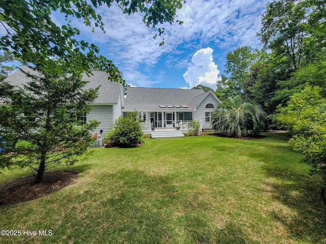 rear view of property featuring roof with shingles and a yard