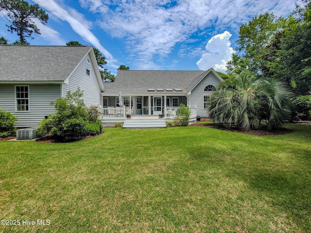 back of house with a shingled roof, a lawn, cooling unit, and a wooden deck