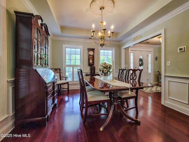 dining space featuring wainscoting, wood finished floors, a tray ceiling, a chandelier, and a decorative wall