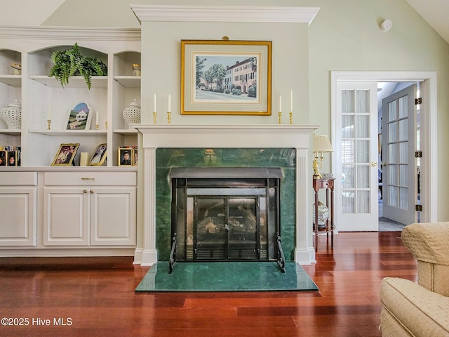 living room with crown molding, lofted ceiling, a fireplace, and wood finished floors