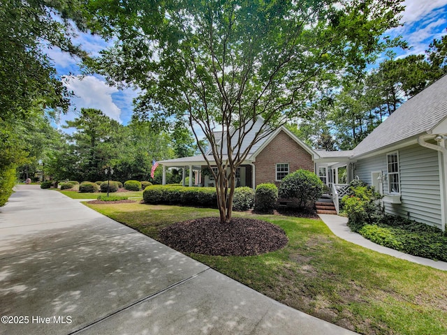 view of front facade with brick siding, crawl space, and a front yard