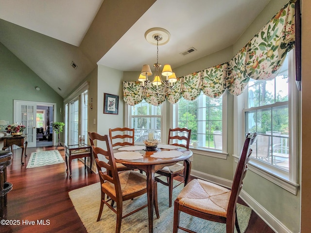 dining area with visible vents, an inviting chandelier, vaulted ceiling, wood finished floors, and baseboards