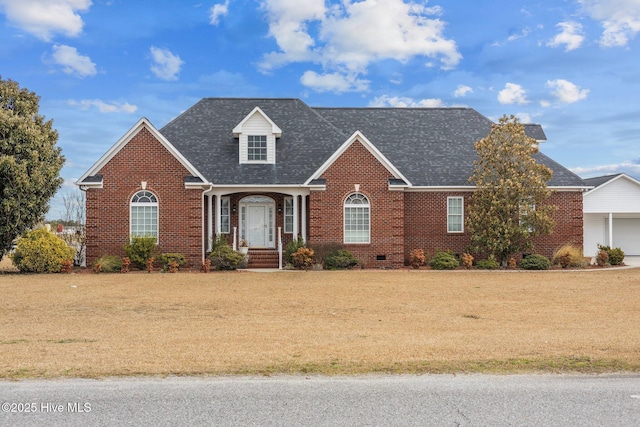 new england style home with roof with shingles, brick siding, crawl space, and a front lawn