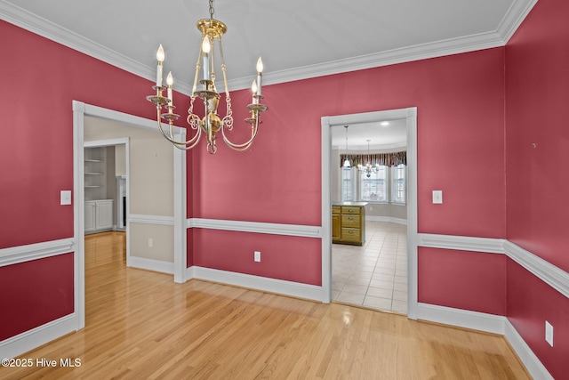 unfurnished dining area featuring an inviting chandelier, baseboards, ornamental molding, and wood finished floors