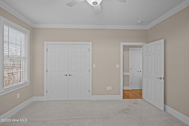 unfurnished bedroom featuring baseboards, a ceiling fan, light colored carpet, ornamental molding, and a closet