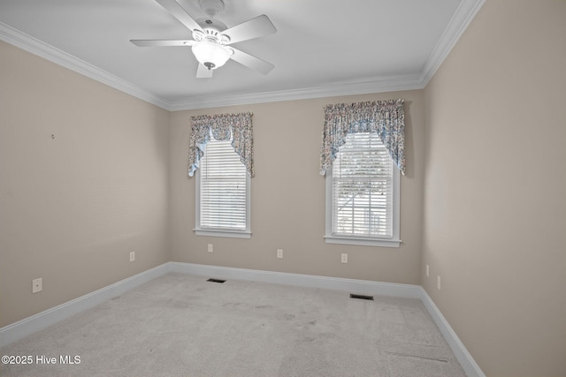 carpeted spare room featuring baseboards, visible vents, ceiling fan, and crown molding