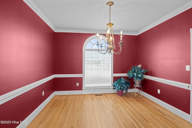 unfurnished dining area with ornamental molding, a notable chandelier, baseboards, and wood finished floors