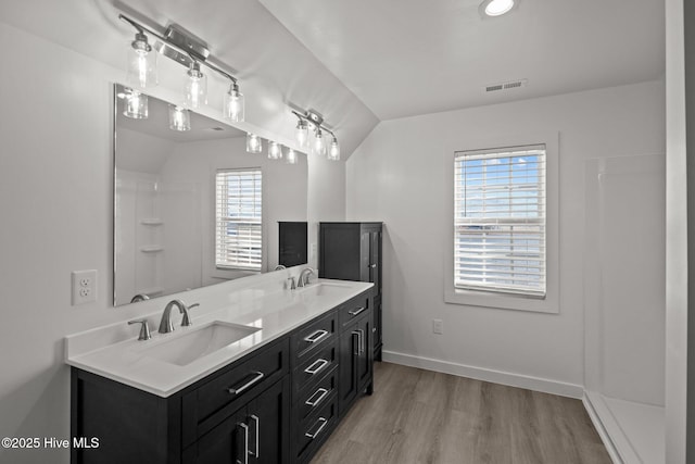 bathroom featuring lofted ceiling, a sink, baseboards, and wood finished floors